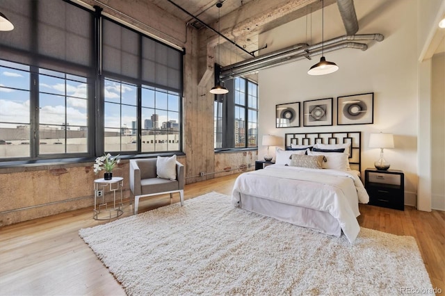 bedroom with a towering ceiling and wood finished floors