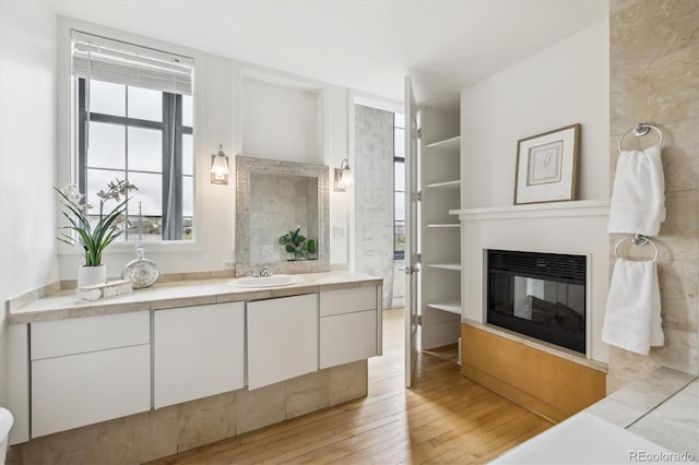 bathroom with wood-type flooring, a glass covered fireplace, and vanity