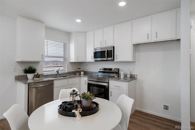 kitchen featuring sink, white cabinetry, light stone counters, dark hardwood / wood-style floors, and stainless steel appliances