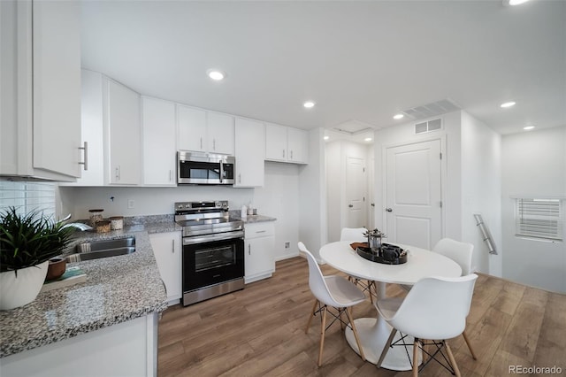 kitchen featuring sink, stainless steel appliances, light hardwood / wood-style floors, light stone countertops, and white cabinets