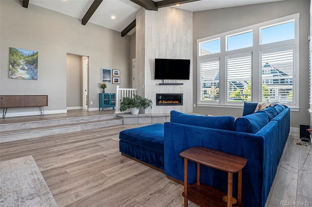 10179 E 59th N Pl, Denver, CO 80238 - living area featuring beamed ceiling, a tiled fireplace, wood finished floors, high vaulted ceiling, and baseboards