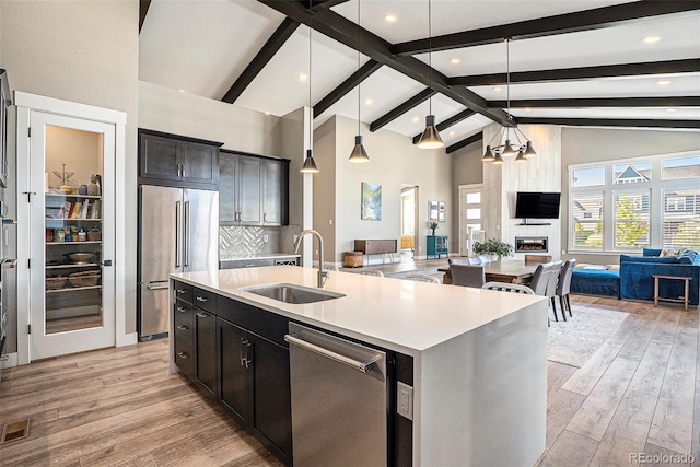 10179 E 59th N Pl, Denver, CO 80238 - kitchen featuring stainless steel appliances, open floor plan, a sink, an island with sink, and beam ceiling