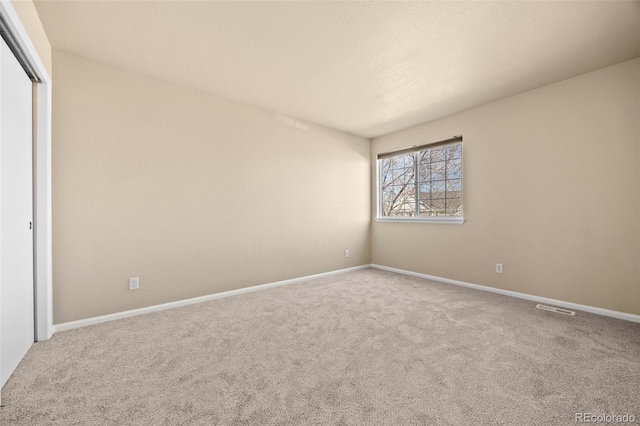 unfurnished bedroom with a closet, carpet flooring, baseboards, and visible vents