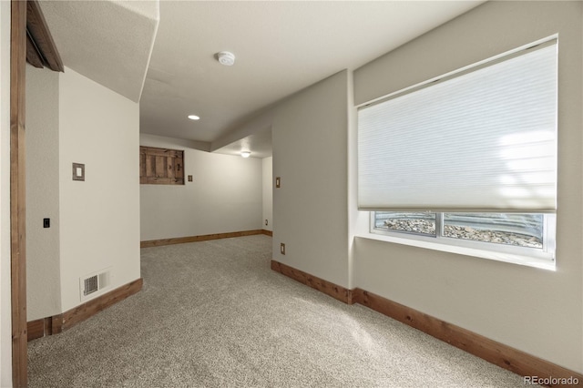 unfurnished room featuring baseboards, visible vents, and carpet