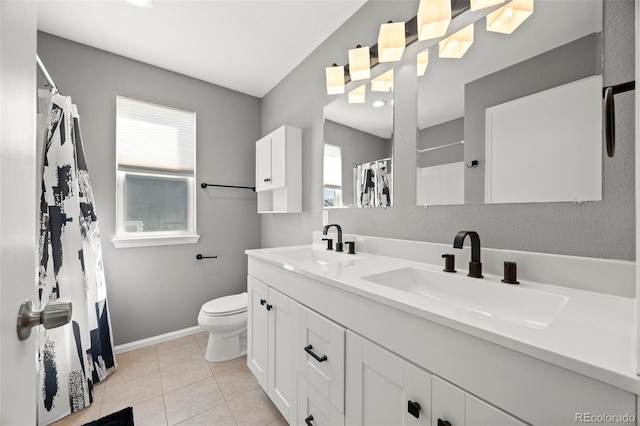 bathroom featuring baseboards, a sink, double vanity, and toilet