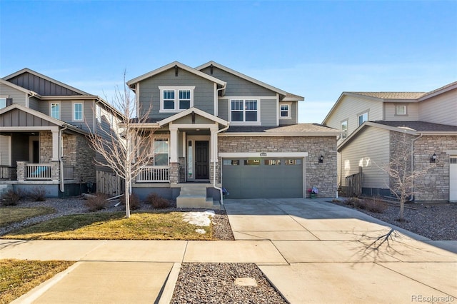 craftsman inspired home with a garage, covered porch, stone siding, and concrete driveway