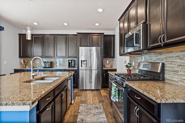 kitchen featuring appliances with stainless steel finishes, dark wood-type flooring, a sink, dark brown cabinetry, and light stone countertops