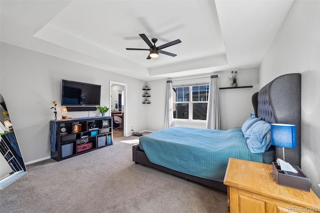 carpeted bedroom featuring ceiling fan, baseboards, and a raised ceiling