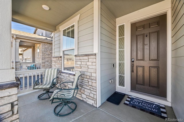 entrance to property featuring stone siding and a porch