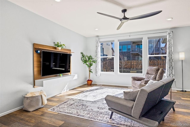 living room with a ceiling fan, baseboards, and wood finished floors