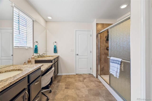 full bath with a stall shower, baseboards, two vanities, and a sink