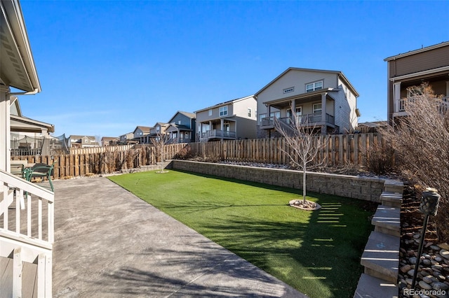 view of yard featuring a patio area, a fenced backyard, and a residential view