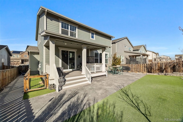 back of house featuring covered porch, a yard, a fenced backyard, and a residential view