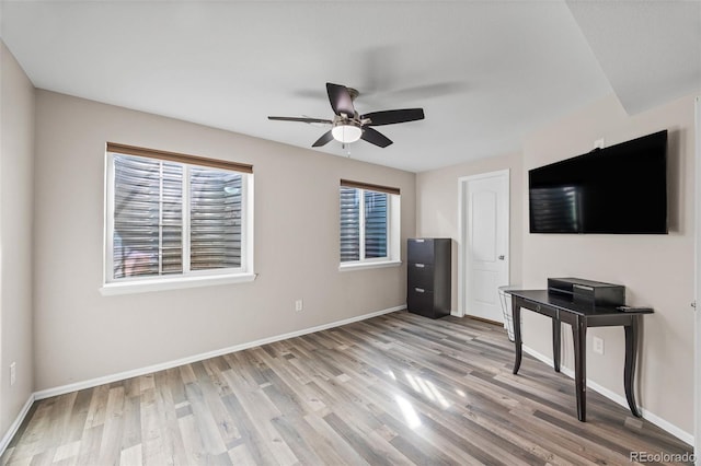 unfurnished living room featuring ceiling fan, a wealth of natural light, light wood-style flooring, and baseboards