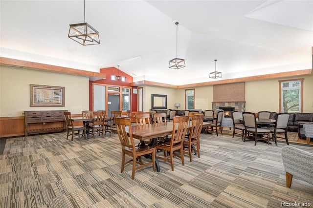 dining room with a lit fireplace, carpet floors, and vaulted ceiling