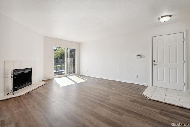 unfurnished living room featuring a tiled fireplace, dark hardwood / wood-style flooring, and a textured ceiling