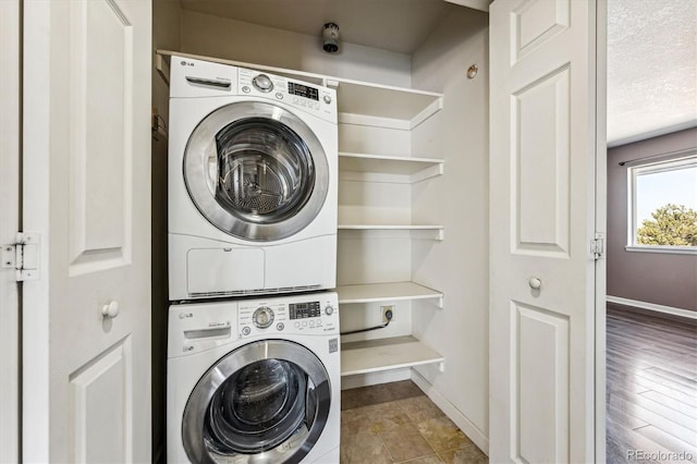 laundry room featuring a textured ceiling, stacked washing maching and dryer, and hardwood / wood-style flooring