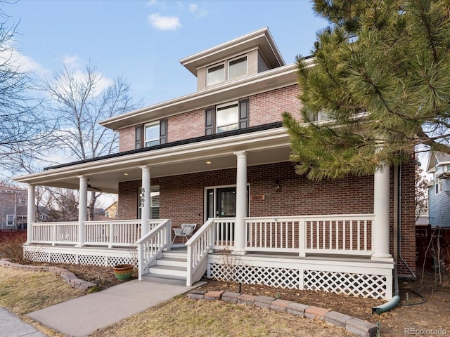 view of front of home with a porch and brick siding