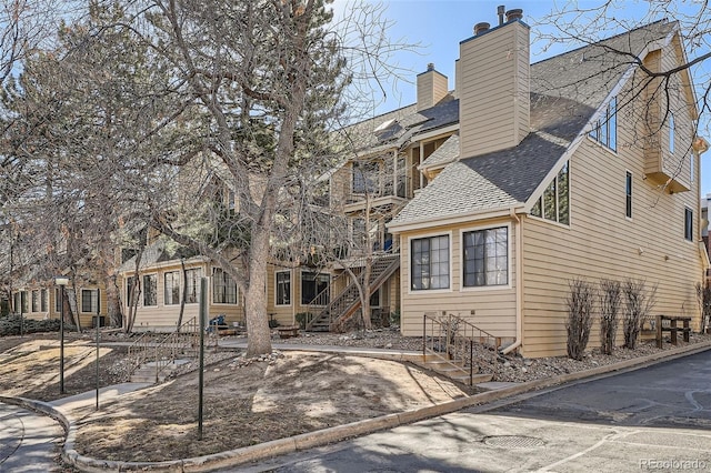 exterior space with stairway and roof with shingles