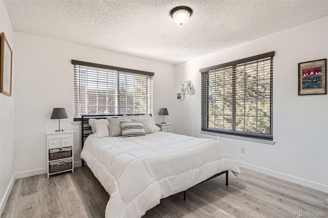 bedroom featuring a textured ceiling, baseboards, and wood finished floors