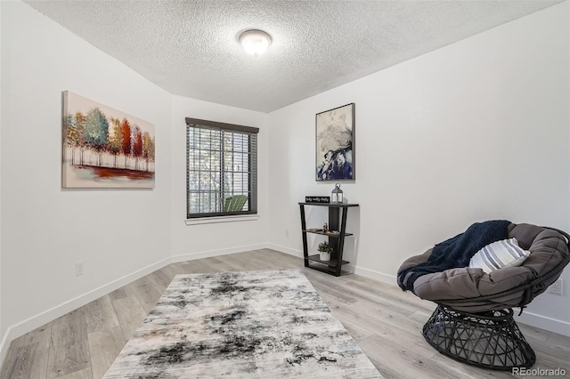 sitting room with a textured ceiling, baseboards, and wood finished floors