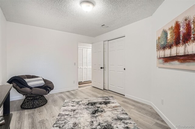 living area featuring light wood-style flooring, visible vents, and baseboards