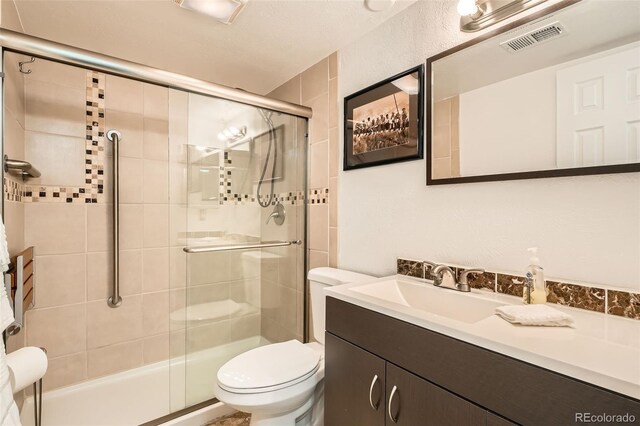 bathroom with toilet, a stall shower, visible vents, and vanity