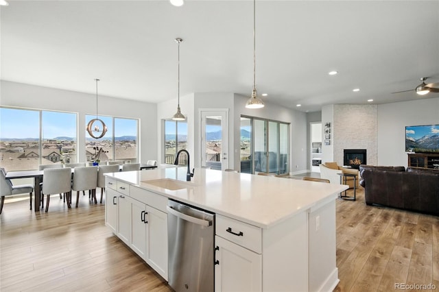 18212 W 95th Pl, Arvada, CO 80007 - kitchen featuring stainless steel dishwasher, a sink, a large fireplace, light wood-style floors, and recessed lighting