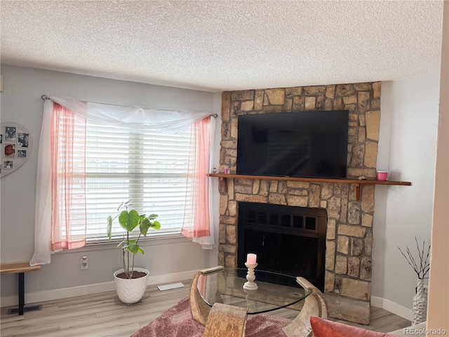 living room with light wood-type flooring, a textured ceiling, and a fireplace