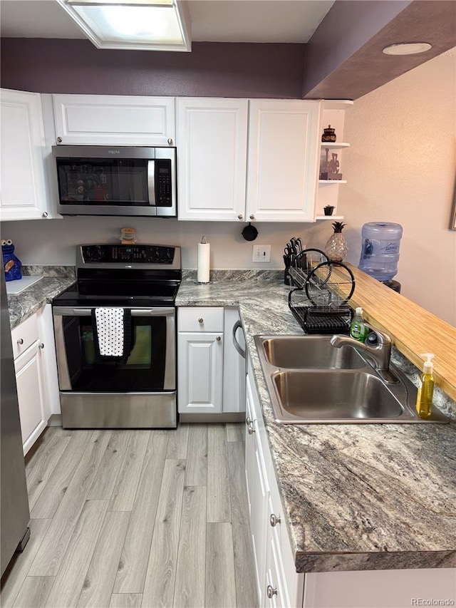 kitchen featuring sink, light hardwood / wood-style floors, white cabinets, and appliances with stainless steel finishes