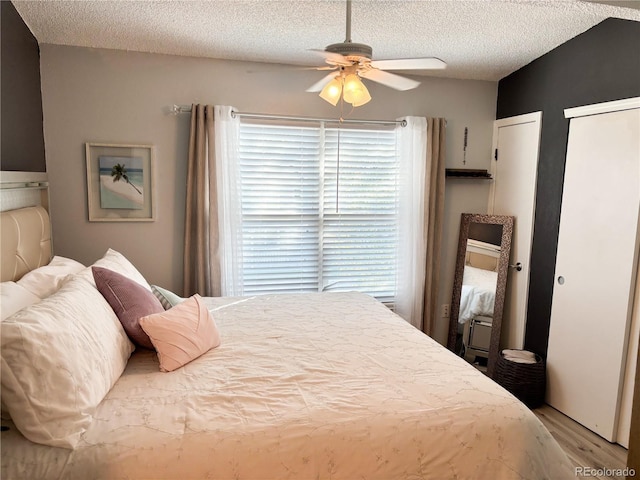 bedroom featuring multiple closets, ceiling fan, a textured ceiling, and light wood-type flooring