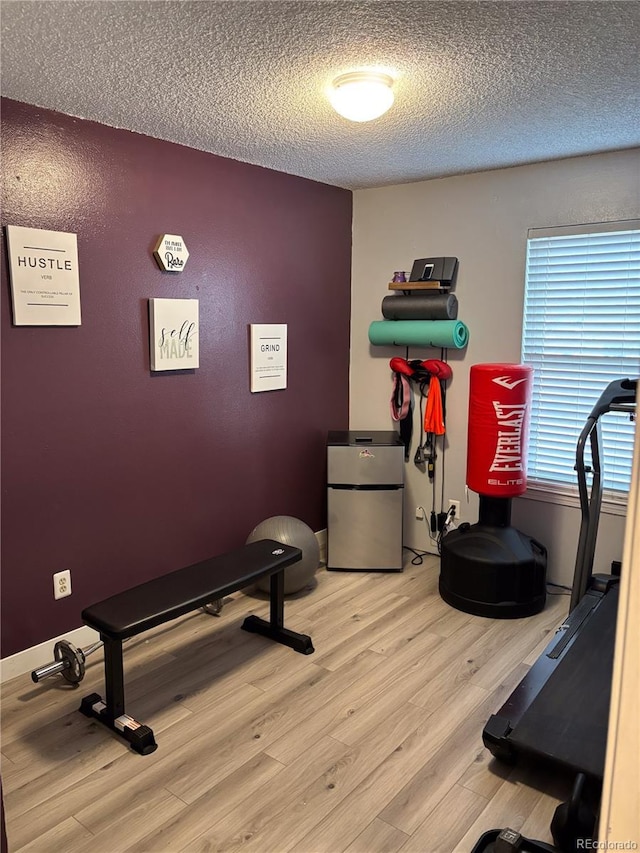 exercise area with a textured ceiling and light wood-type flooring