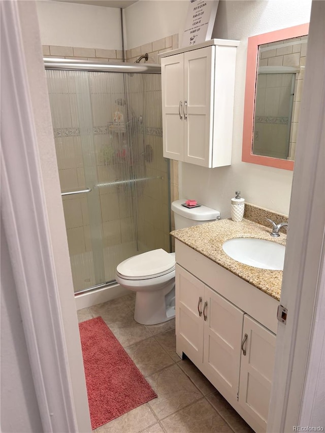 bathroom featuring vanity, an enclosed shower, tile patterned floors, and toilet