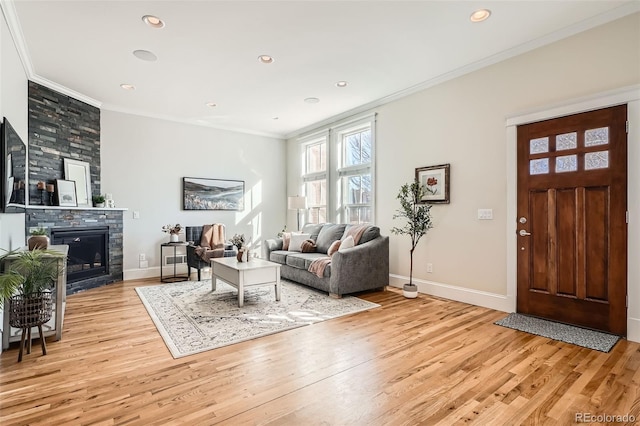 living room with a large fireplace, baseboards, crown molding, and light wood finished floors