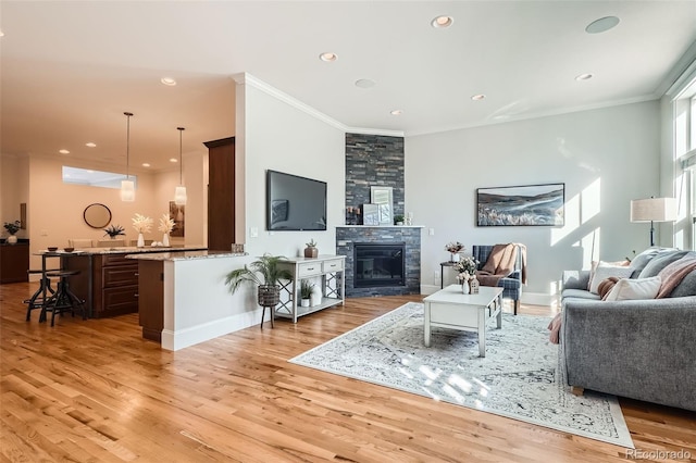 living room featuring light wood-style floors, a fireplace, crown molding, and recessed lighting