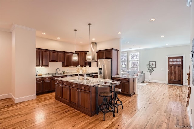 kitchen featuring a sink, a kitchen island, light wood-style floors, high end fridge, and dark brown cabinets