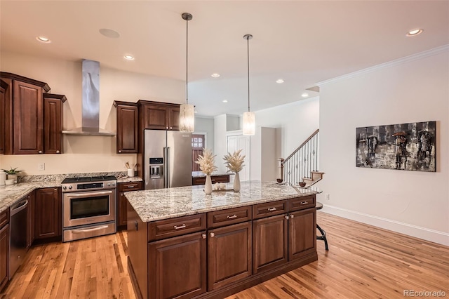 kitchen with light wood-type flooring, wall chimney exhaust hood, a kitchen island, and appliances with stainless steel finishes