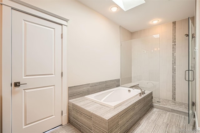 bathroom featuring a skylight, a bath, and a stall shower