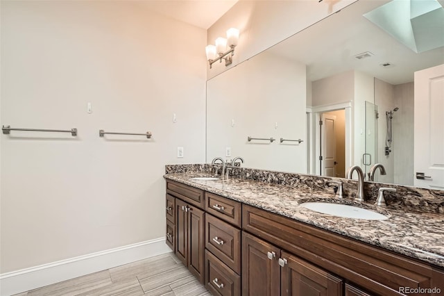 bathroom featuring a sink, a shower stall, baseboards, and double vanity