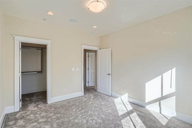 unfurnished bedroom with recessed lighting, carpet flooring, baseboards, a closet, and a walk in closet