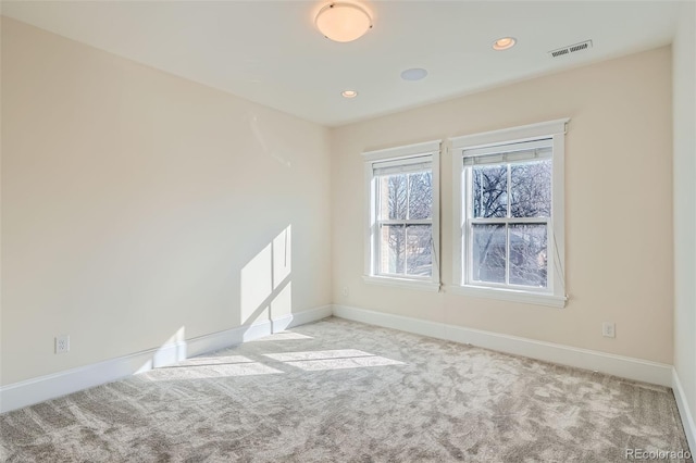 empty room with carpet floors, recessed lighting, visible vents, and baseboards