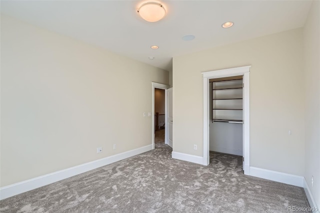 unfurnished bedroom featuring carpet floors, a spacious closet, recessed lighting, and baseboards