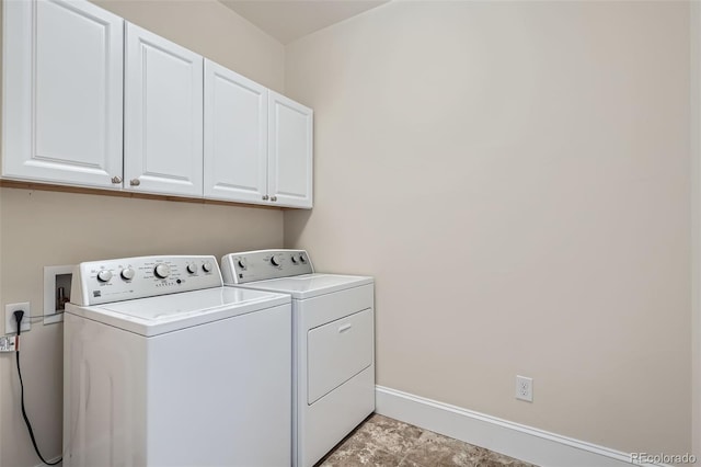 washroom featuring washer and clothes dryer, cabinet space, and baseboards