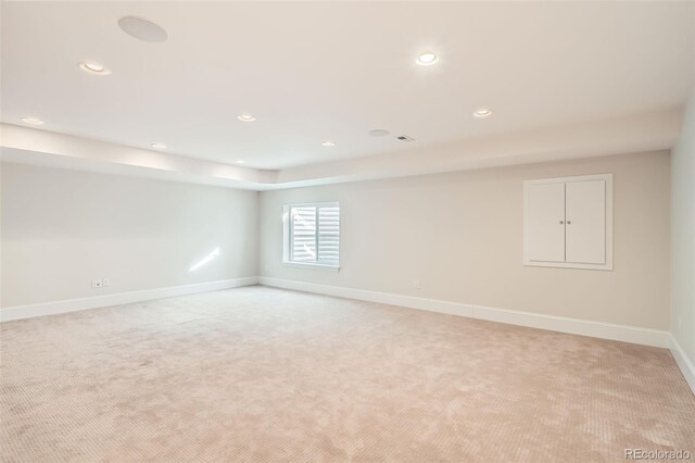 empty room featuring recessed lighting, light colored carpet, and baseboards