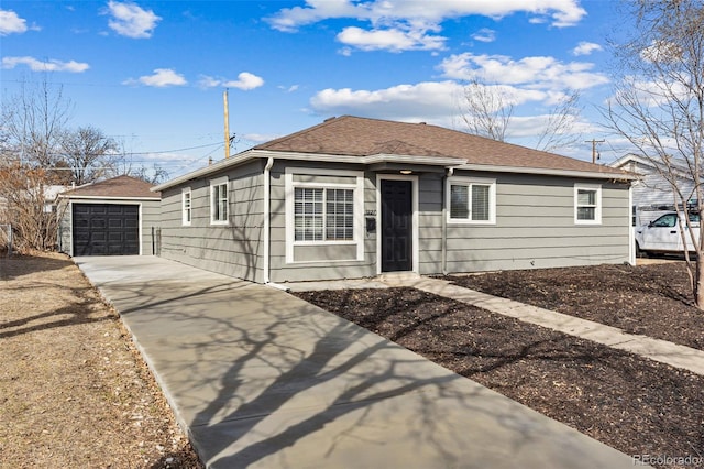 view of front of property with a detached garage, roof with shingles, an outdoor structure, and driveway