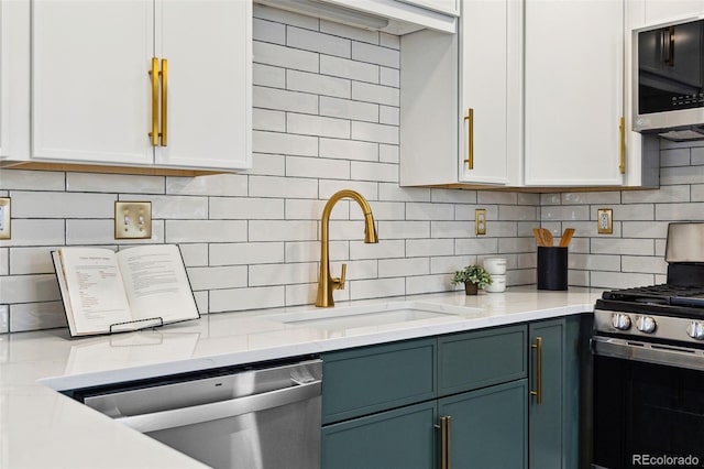 kitchen with a sink, stainless steel appliances, decorative backsplash, and white cabinetry