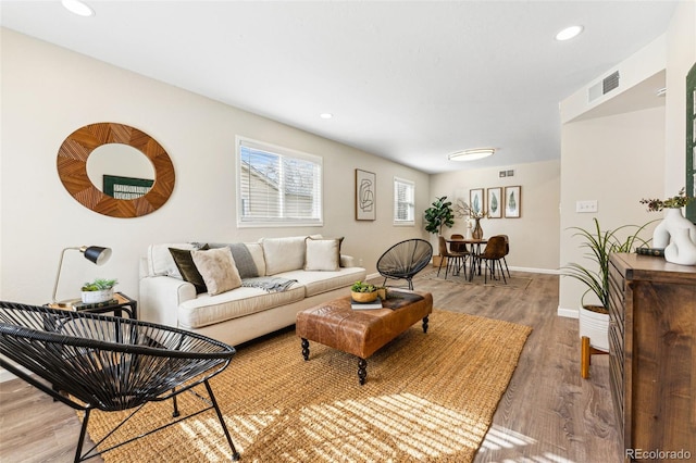 living room featuring recessed lighting, light wood-type flooring, baseboards, and visible vents