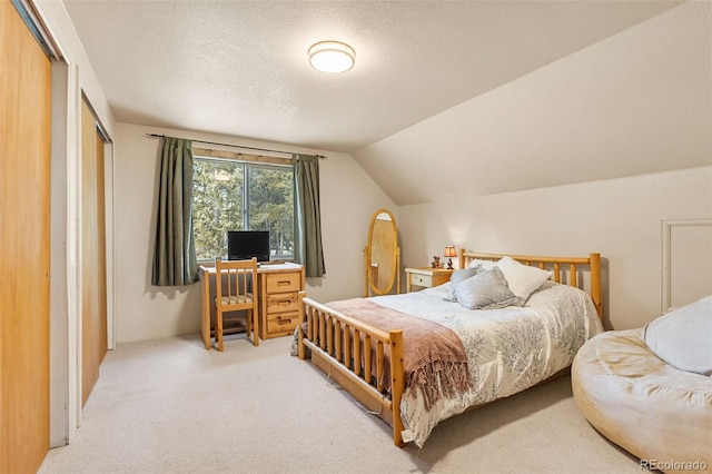 bedroom with light carpet, a textured ceiling, vaulted ceiling, and a closet