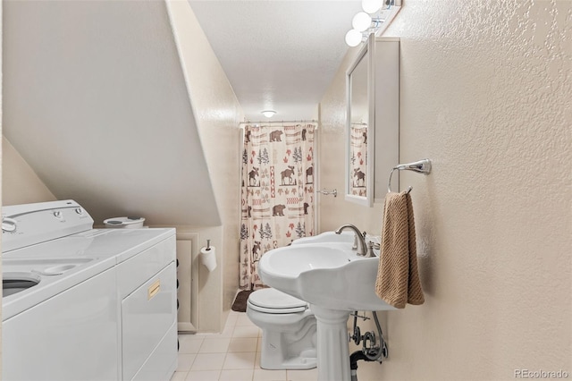 bathroom with a textured wall, curtained shower, washing machine and dryer, toilet, and tile patterned floors