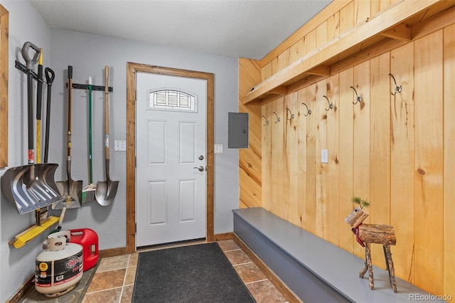 mudroom with electric panel, wooden walls, baseboards, and tile patterned floors